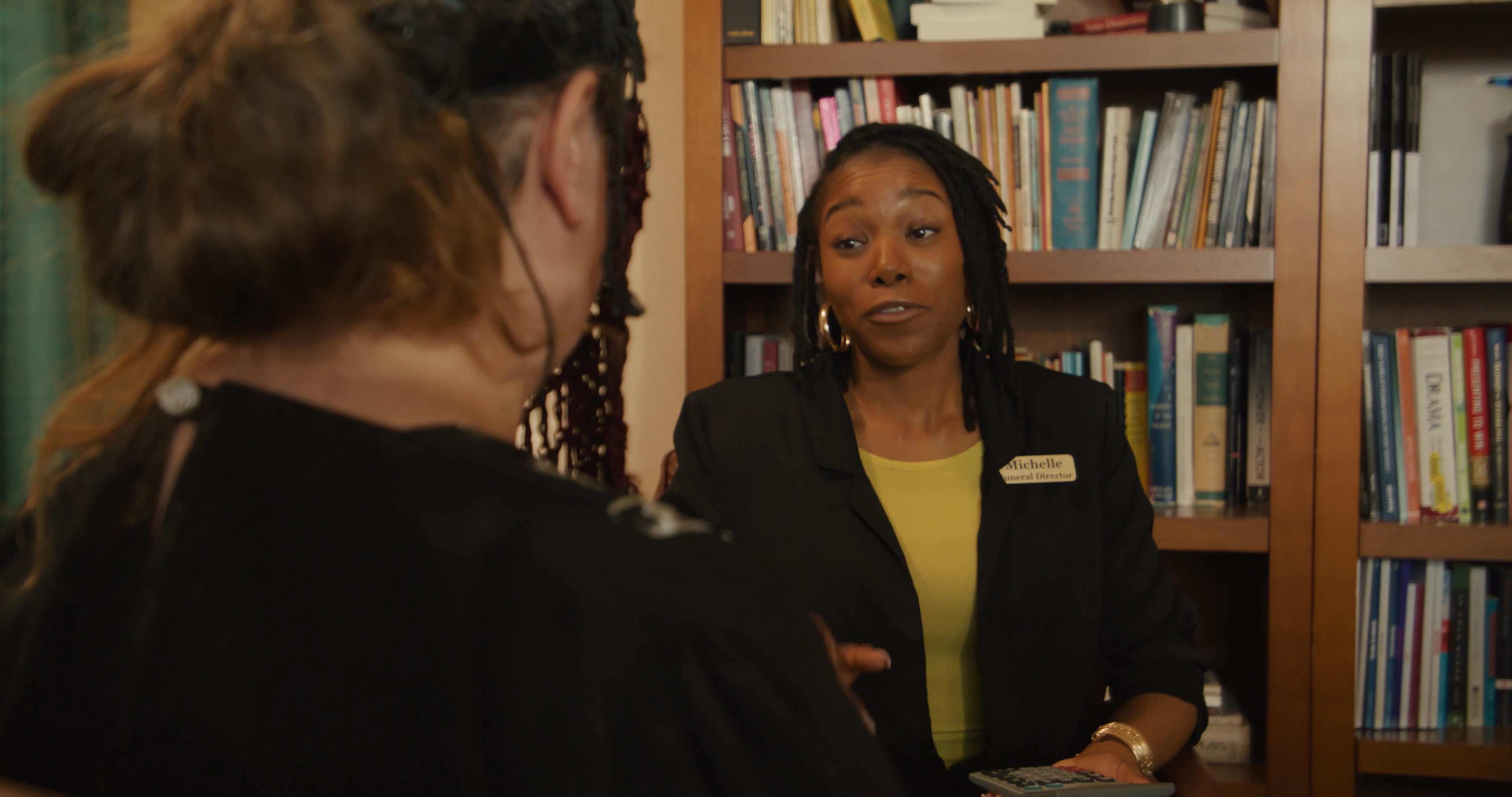 Two individuals engage in a structured, professional consultation within an office environment, utilizing a calculator to review financial details.