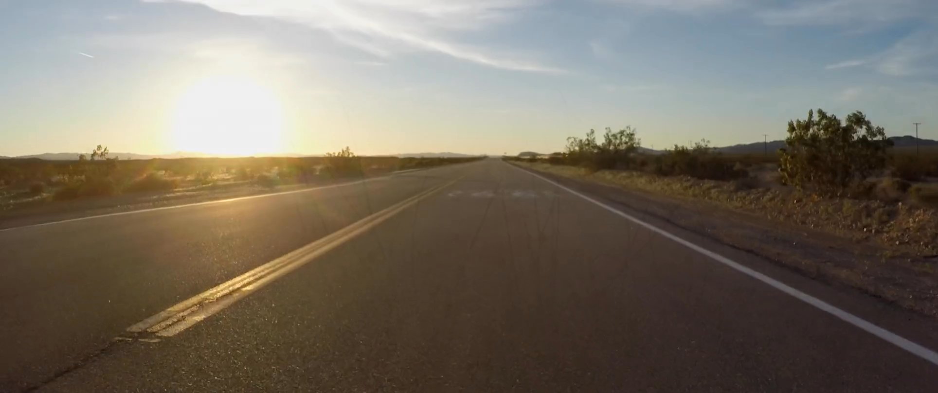 The perspective shifts from a scenic coastal hillside to a sun-drenched drive along the iconic Route 66. The sequence captures the transition from natural shoreline landscapes to the expansive desert vistas of a classic American road trip.