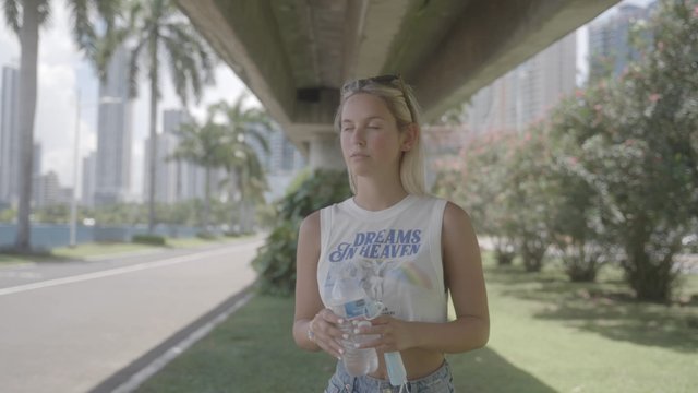Blonde girl drinking water on a hot day