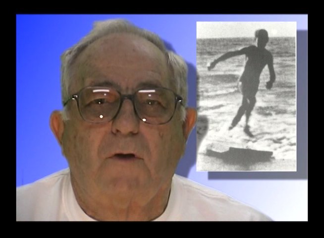 An elderly man discusses his past as he reviews vintage black-and-white film footage of himself surfing on the ocean.