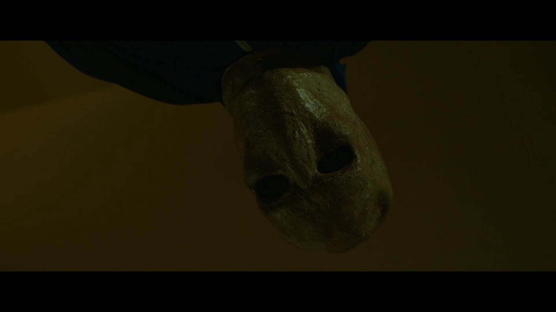 A masked intruder watches over a sleeping family in their bedroom during the night. The scene uses a dark, claustrophobic aesthetic to build tension.