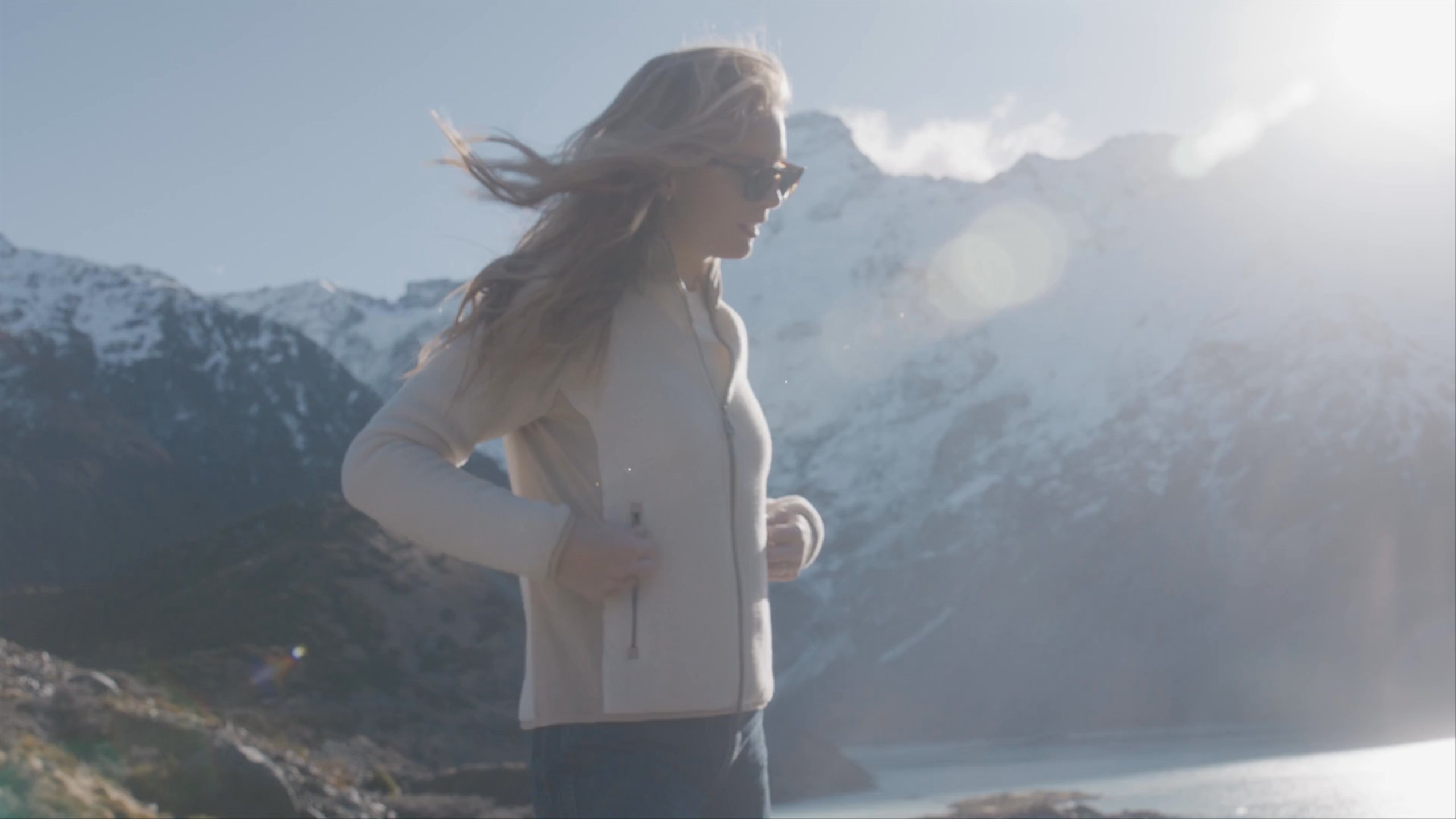 A woman wearing walsh full zip relaxes and walks at the foot of snow mountains and by a lake in New Zealand.