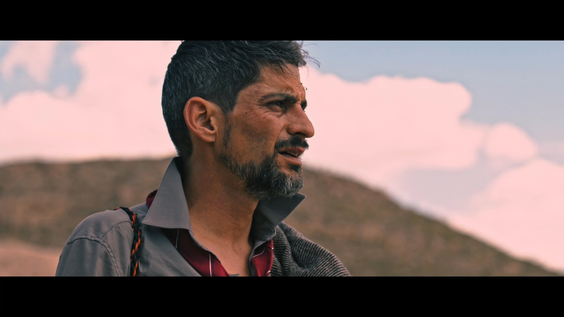 Two men navigate a rugged, sun-drenched desert landscape while scanning the horizon. Their journey through the arid terrain highlights the challenges of wilderness travel.