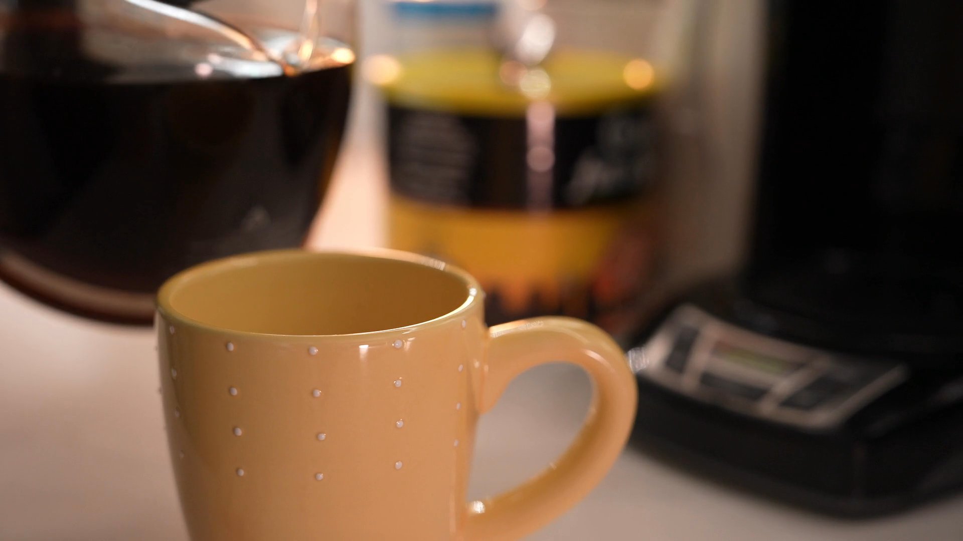 A woman wakes up in her home and proceeds to pour a cup of fresh coffee in the kitchen. She maintains a serious demeanor throughout her quiet morning ritual.