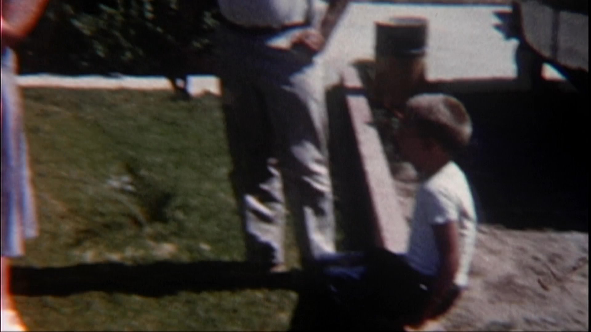 A woman holds an infant in a sunlit backyard while a man stands nearby, followed by scenes of children playing on a lawn and a woman reflecting on the memories.