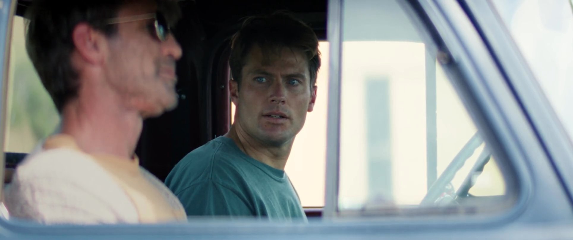 Two men engage in a serious, focused conversation while sitting inside the cab of a truck.