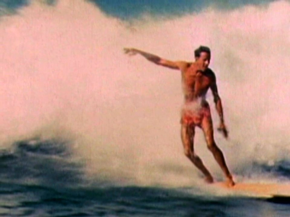 Historical footage chronicles the surfing career of big wave pioneer Fred Van Dyke, transitioning into an interview session with the legend himself. The sequence contrasts his early athletic exploits with his later life reflections.