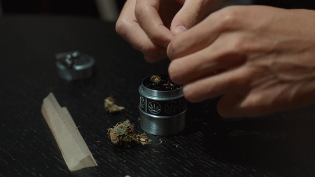 A man preparing weed to be ground up