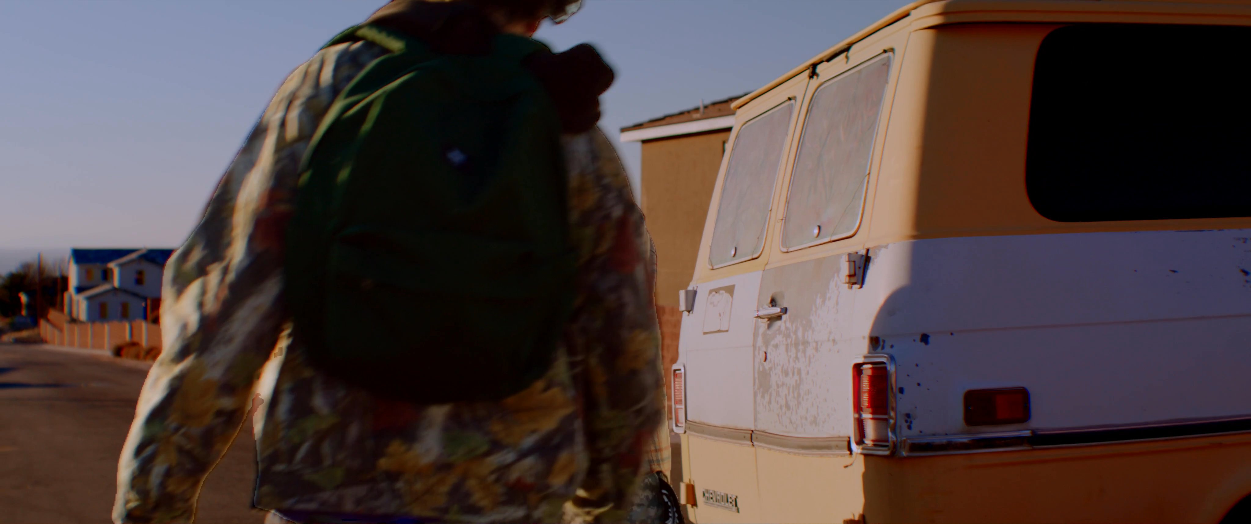 A group of young men engage in a tense verbal and physical altercation next to a vintage van in a quiet residential neighborhood.