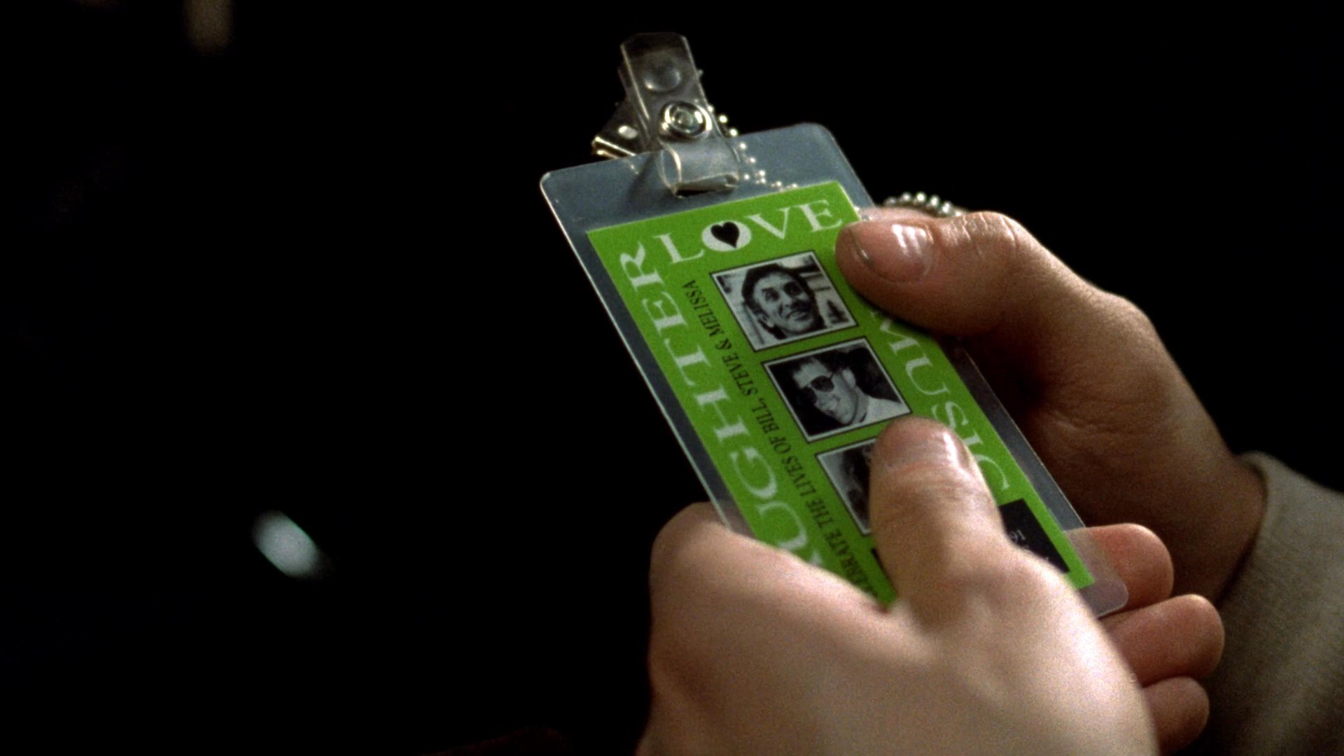 A passenger seated on a moving train examines an identification badge featuring photographs before gazing out the window during transit.