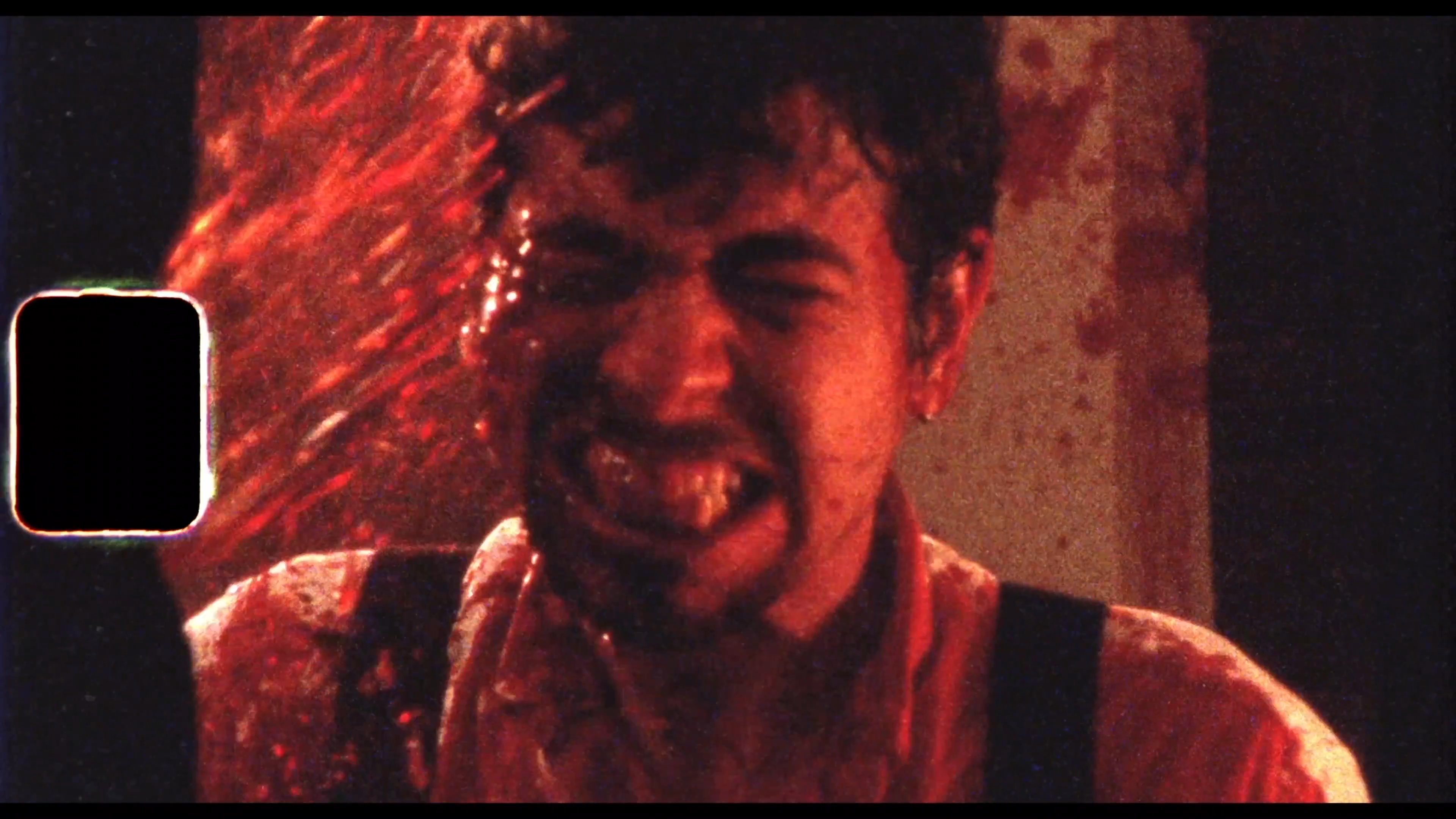 A man in a white shirt frantically operates a chainsaw, resulting in a sudden, violent explosion of red fluid and the appearance of a lobster in the chaotic aftermath.