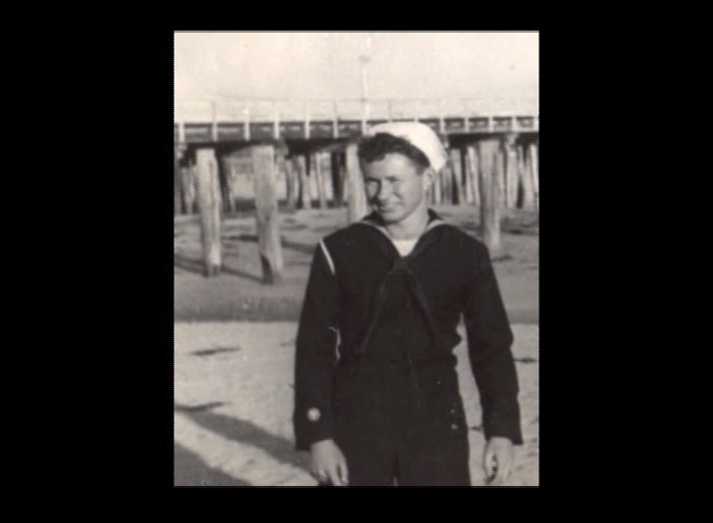 An elderly veteran shares personal reflections on his service, juxtaposed with archival imagery of himself in his naval uniform.