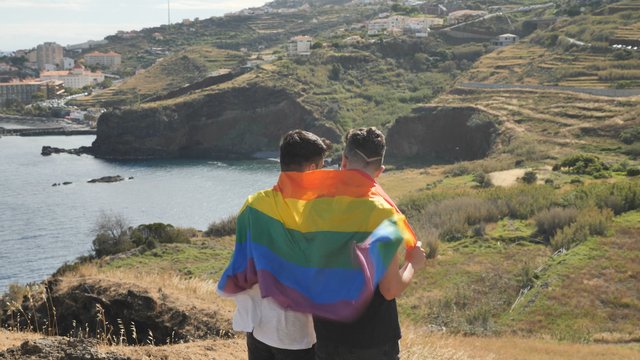 Gay couple hugging with pride flag 