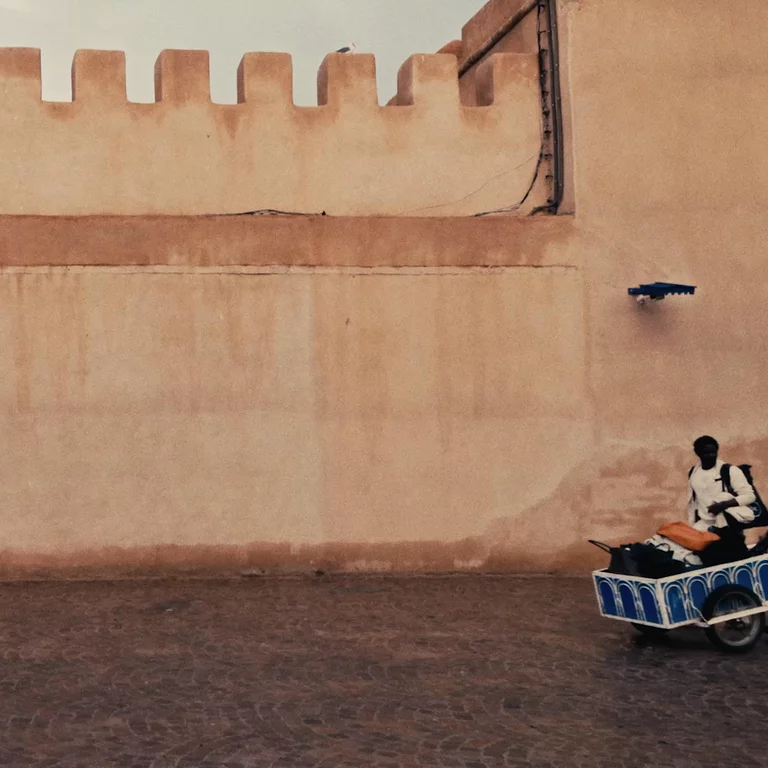 Video of three assistants moving luggage on carts in an old Moroccan plaza