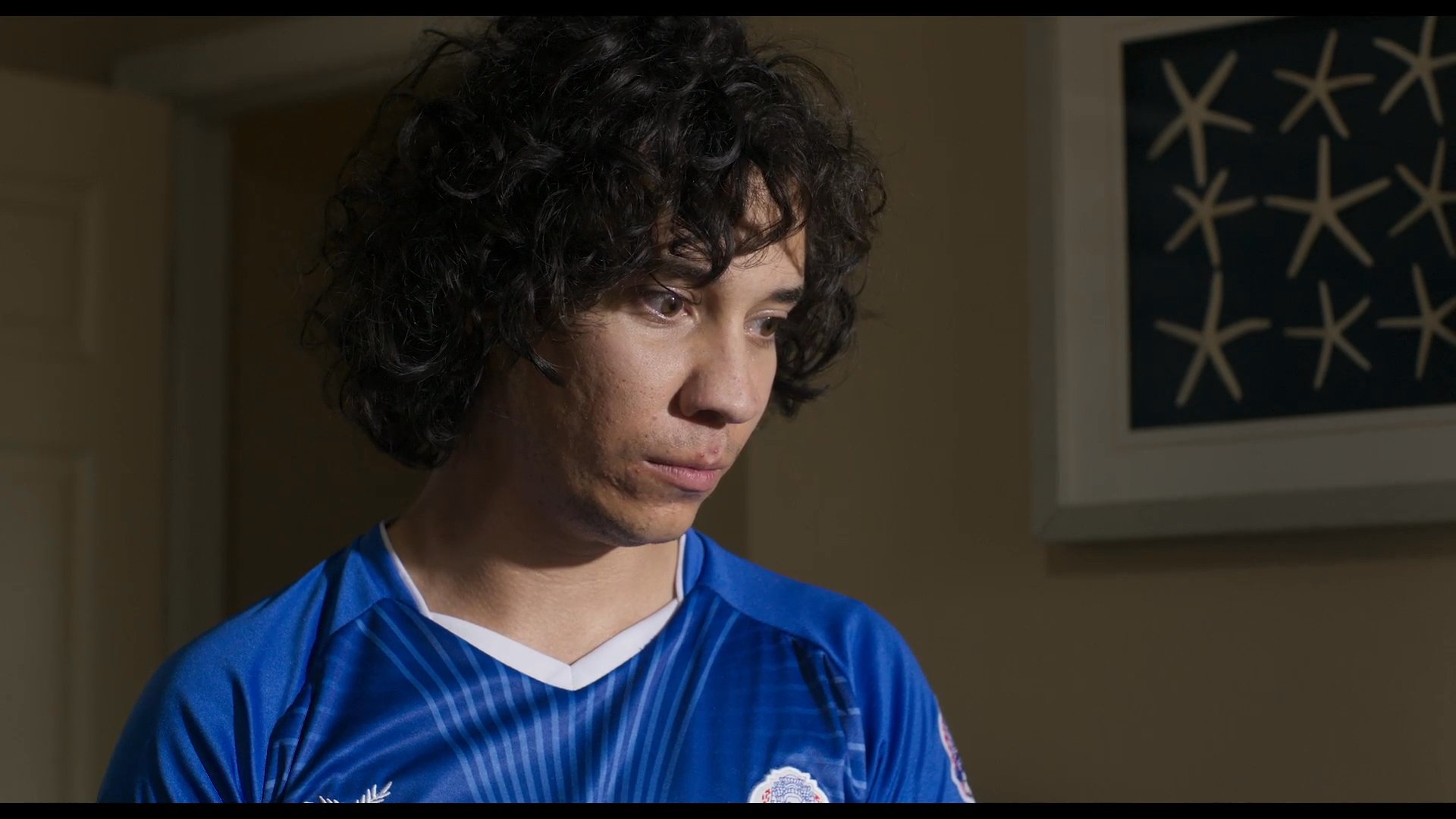 A tense argument between a mother and her son concludes with the mother retreating to a bathroom in distress. The son remains in the hallway while the mother isolates herself, highlighting the emotional weight of their interaction.