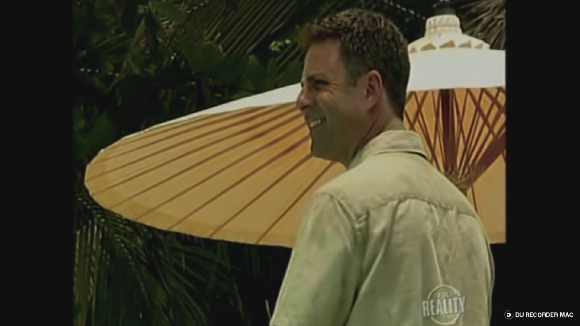 Participants engage in a group discussion about dating strategies at a tropical beach resort, accompanied by on-screen commentary regarding relationship dynamics.
