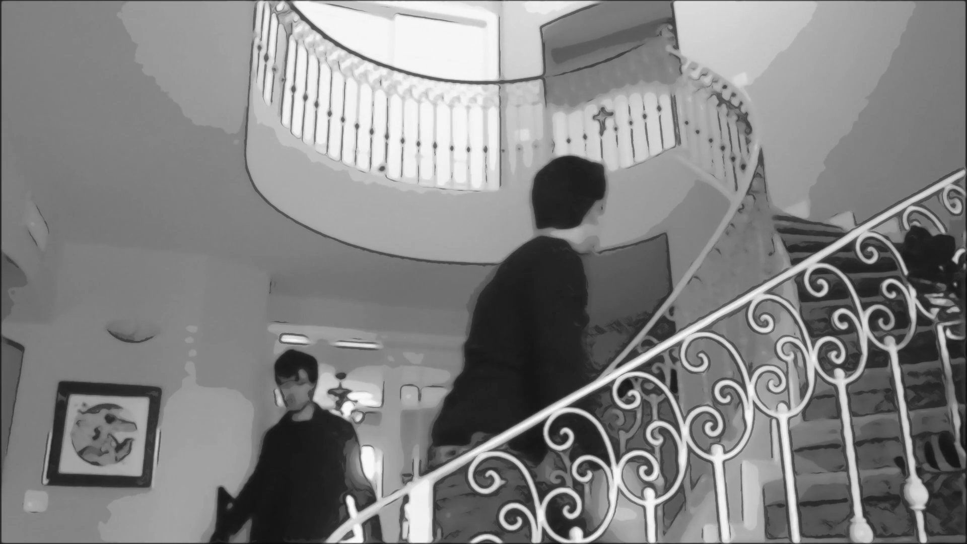Two individuals engage in a tense tactical pursuit through a residential foyer and up a spiral staircase. One individual moves defensively with a firearm while maneuvering through the multi-level interior.