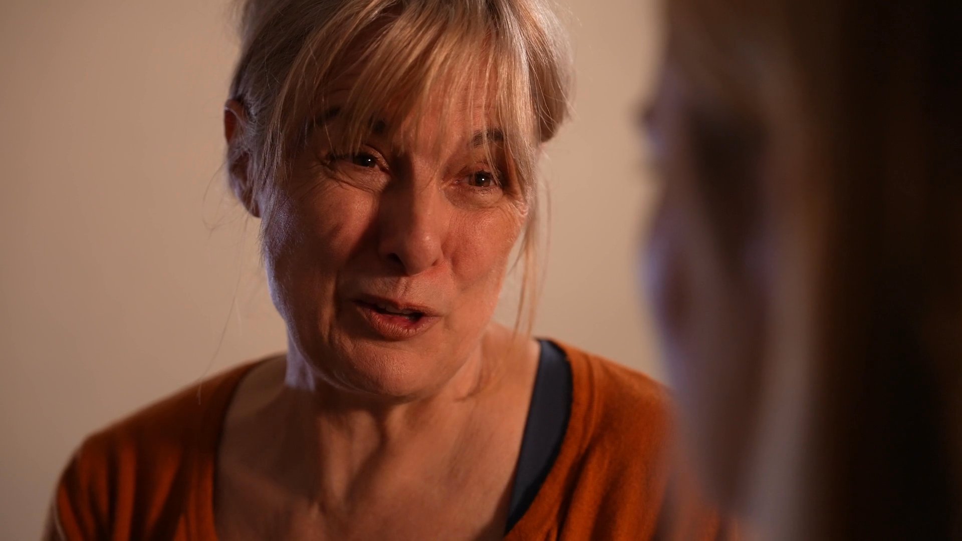 An older woman engages in a supportive and empathetic conversation with a younger woman. The interaction centers on emotional connection and guidance within a calm, indoor environment.