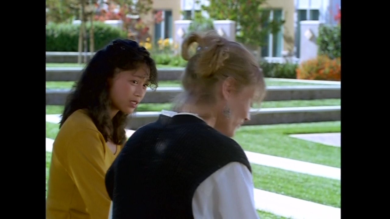 A woman comforts another person outdoors in a garden setting before transitioning to scenes of people interacting inside a restaurant.