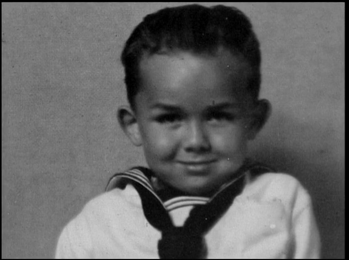 Powerful ocean waves transition into a nostalgic portrait of John Kelly, tracing his life journey from a young boy to an elder reflecting on his experiences.