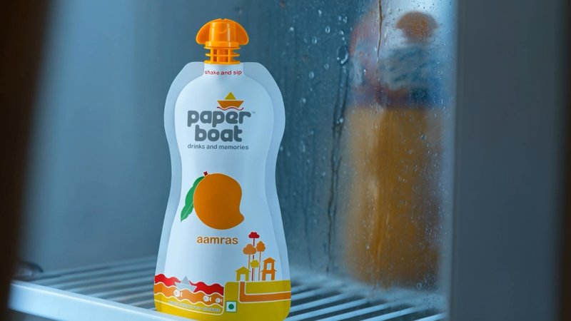 Still from the Paper Boat AI brand film: an aamras pouch in a fridge