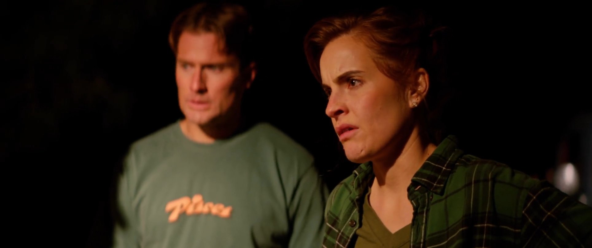 A group of individuals engage in a heated, high-tension confrontation within a dimly lit indoor setting at night. The dialogue and body language reveal underlying interpersonal friction as the participants interact.