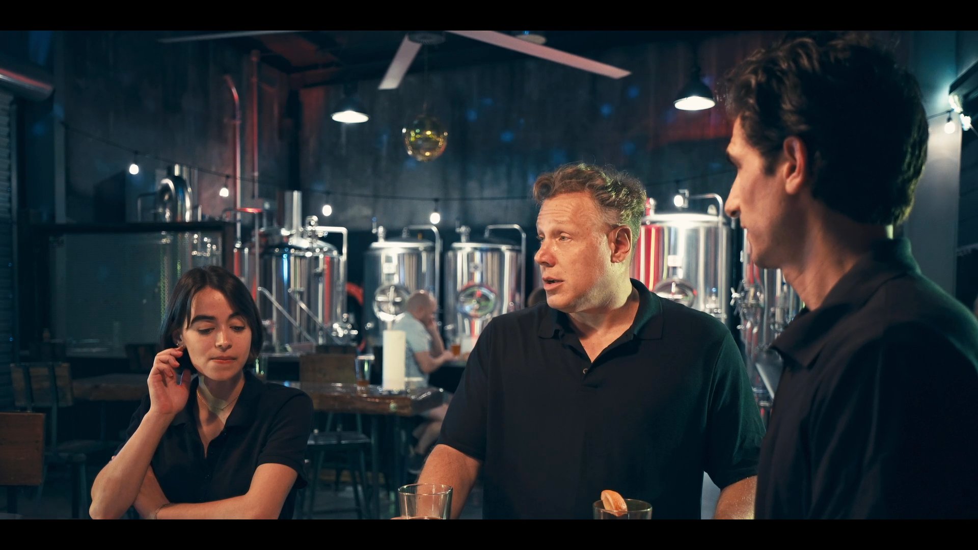 Professional staff interact in a brewery taproom setting before transitioning into a focused interview regarding brewing operations. The discussion highlights the technical environment and operational expertise within a commercial craft brewery.