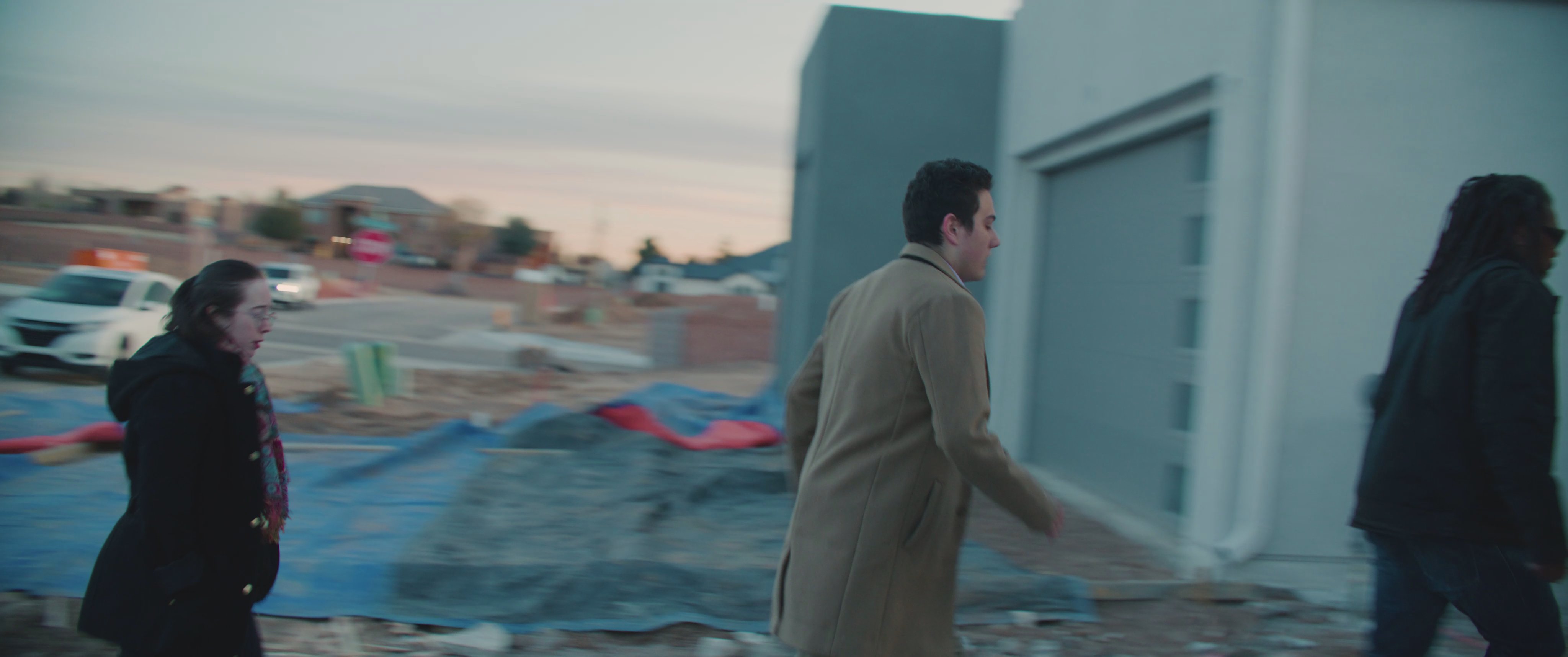 An armed individual confronts a man outside a residential property before pursuing a group of people through a suburban neighborhood.
