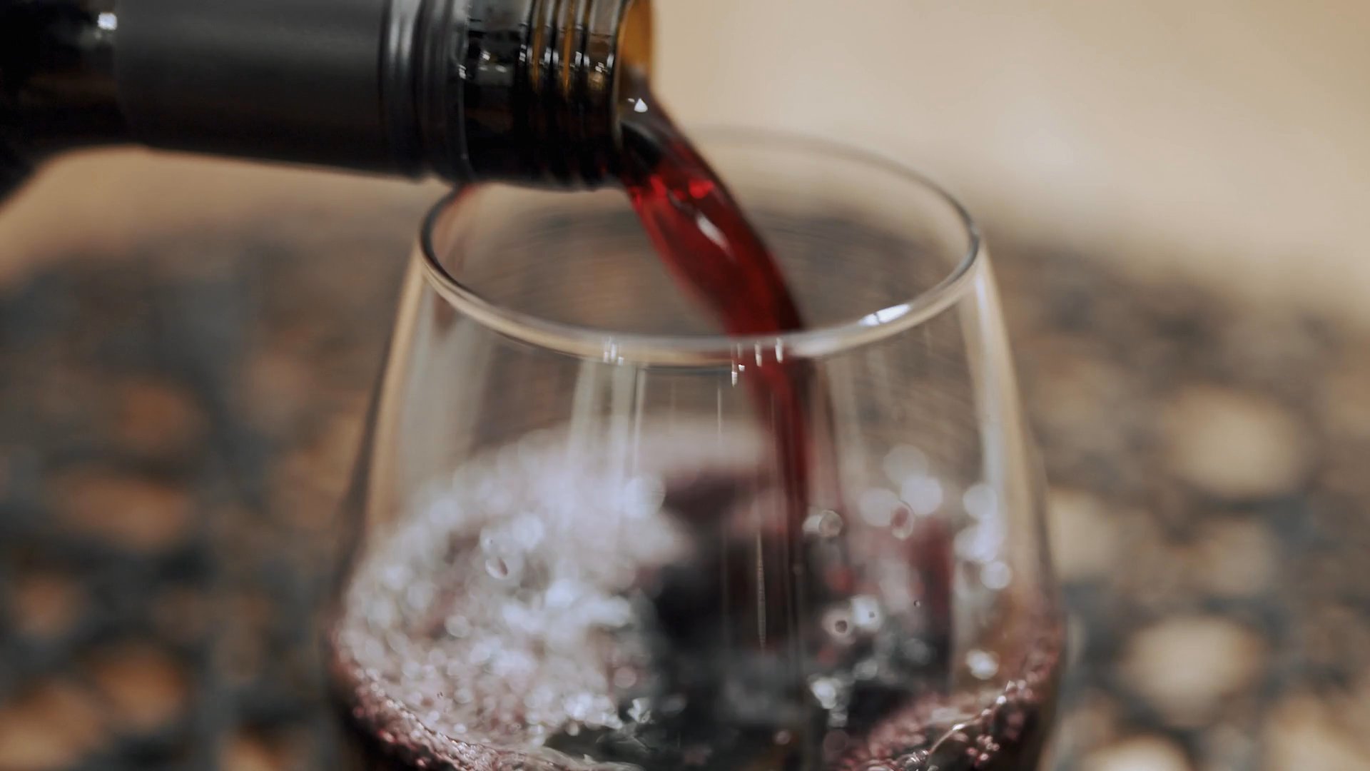 A man finishes his commute and enters a modern home where a woman reads at a large dining table, shortly after he pours a glass of red wine.