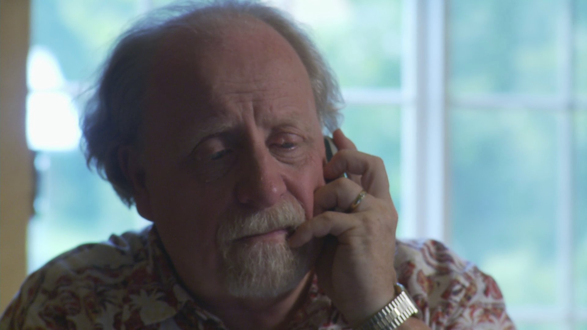 An elderly man and a young woman hold an emotional phone conversation while in separate locations. They subsequently meet in a wooded outdoor area to connect in person.