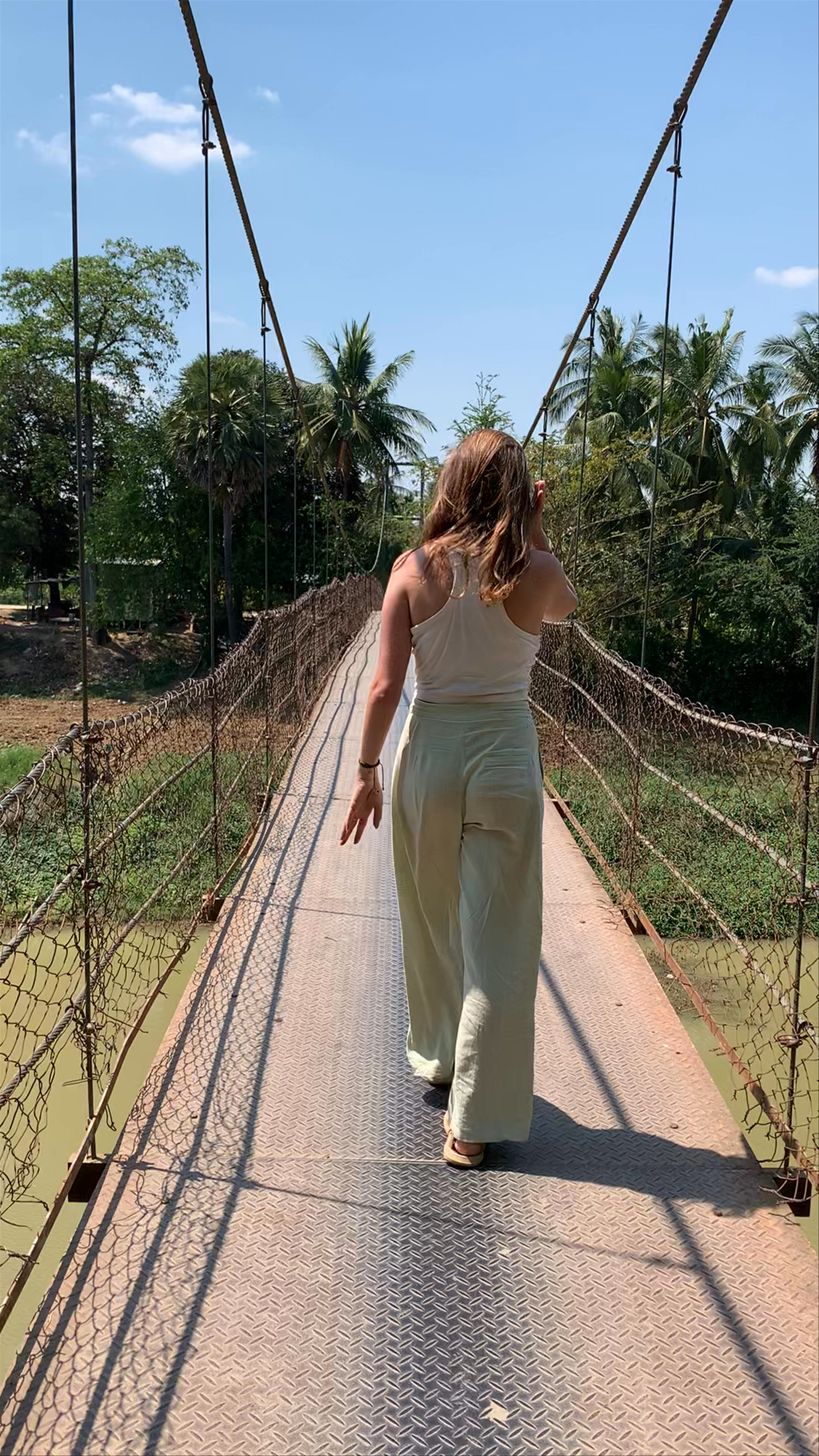 Sunlit Stroll Across a Rustic Suspension Bridge in Battambang, Cambodia