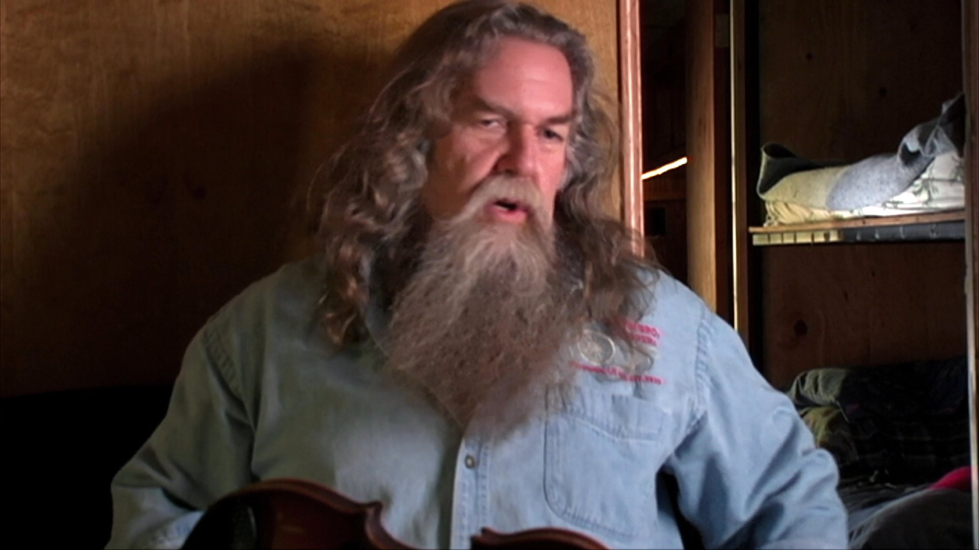 Musician Harry Fryed of The Fryed Brothers Band shares personal anecdotes during an interview. He gestures while speaking, providing insight into his experiences as a performer.