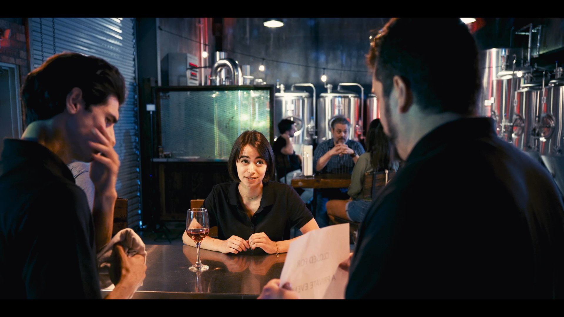 Professional associates meet at a brewery bar to review documents and discuss operational details in a collaborative setting.