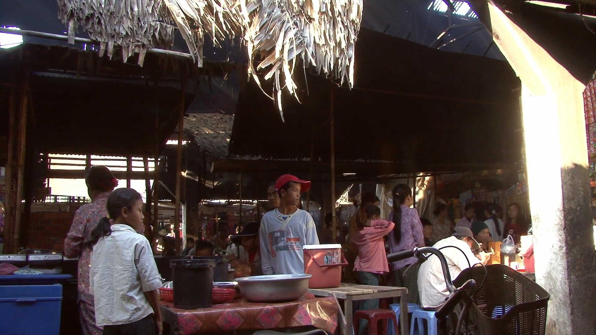 A bustling market environment features vendors preparing food and shoppers navigating the busy stalls. The sequence highlights local culinary customs and daily trade activity.