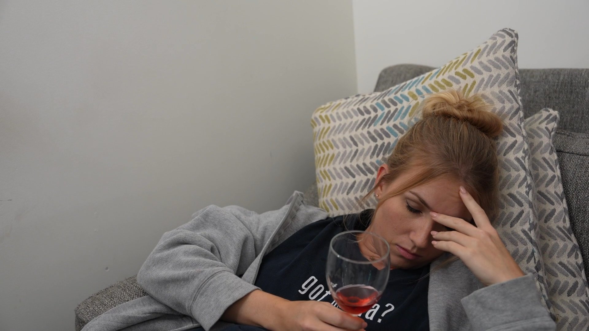 A woman wipes down a kitchen counter while her daughter rests on a nearby couch, creating an atmosphere of palpable domestic tension. The two individuals navigate a strained interaction within the shared home environment.