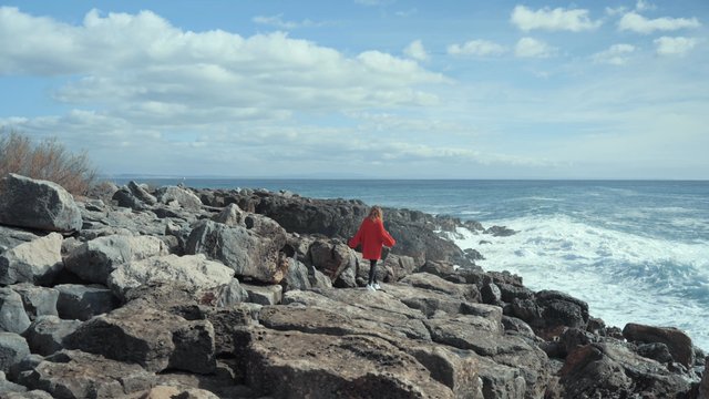 A girl walking on the rocky coast