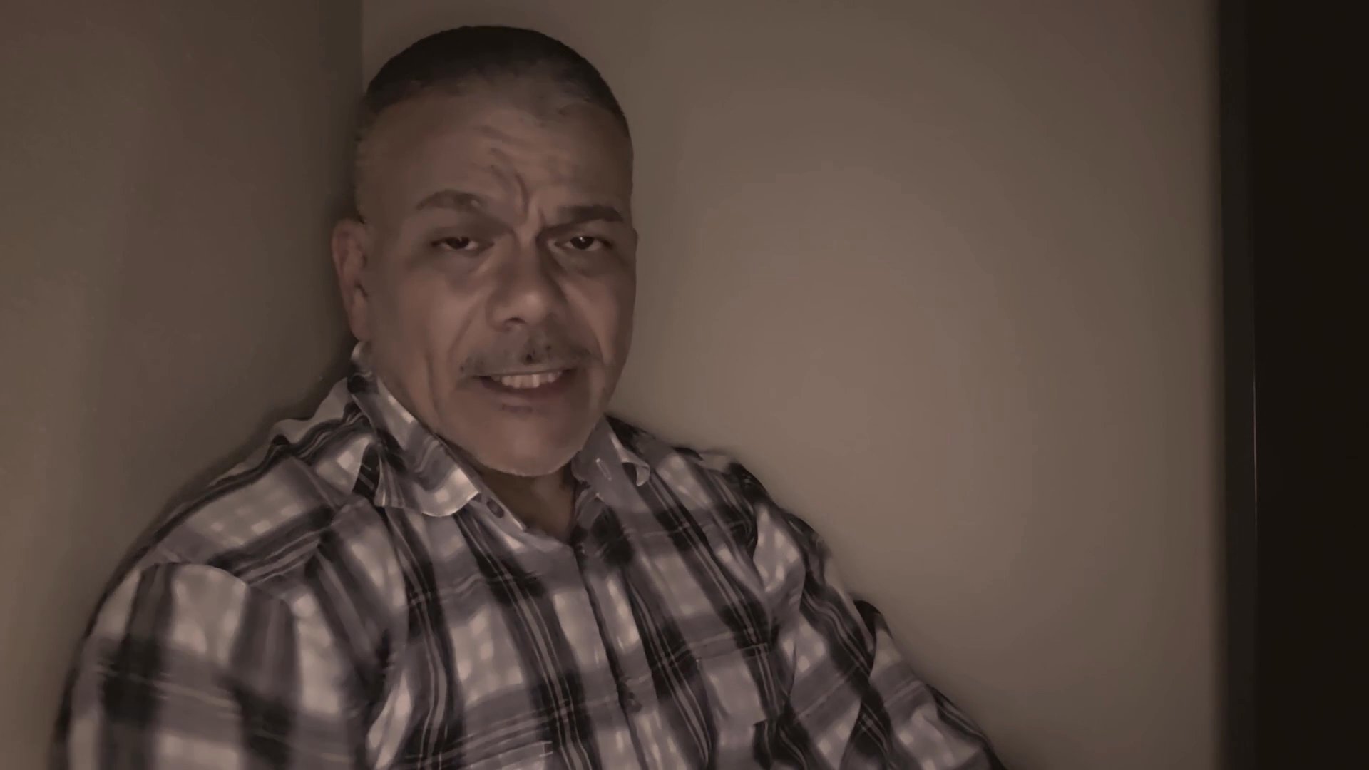 A man in a plaid shirt speaks directly to the camera in an indoor setting, maintaining a consistent engagement with the viewer throughout the sequence.