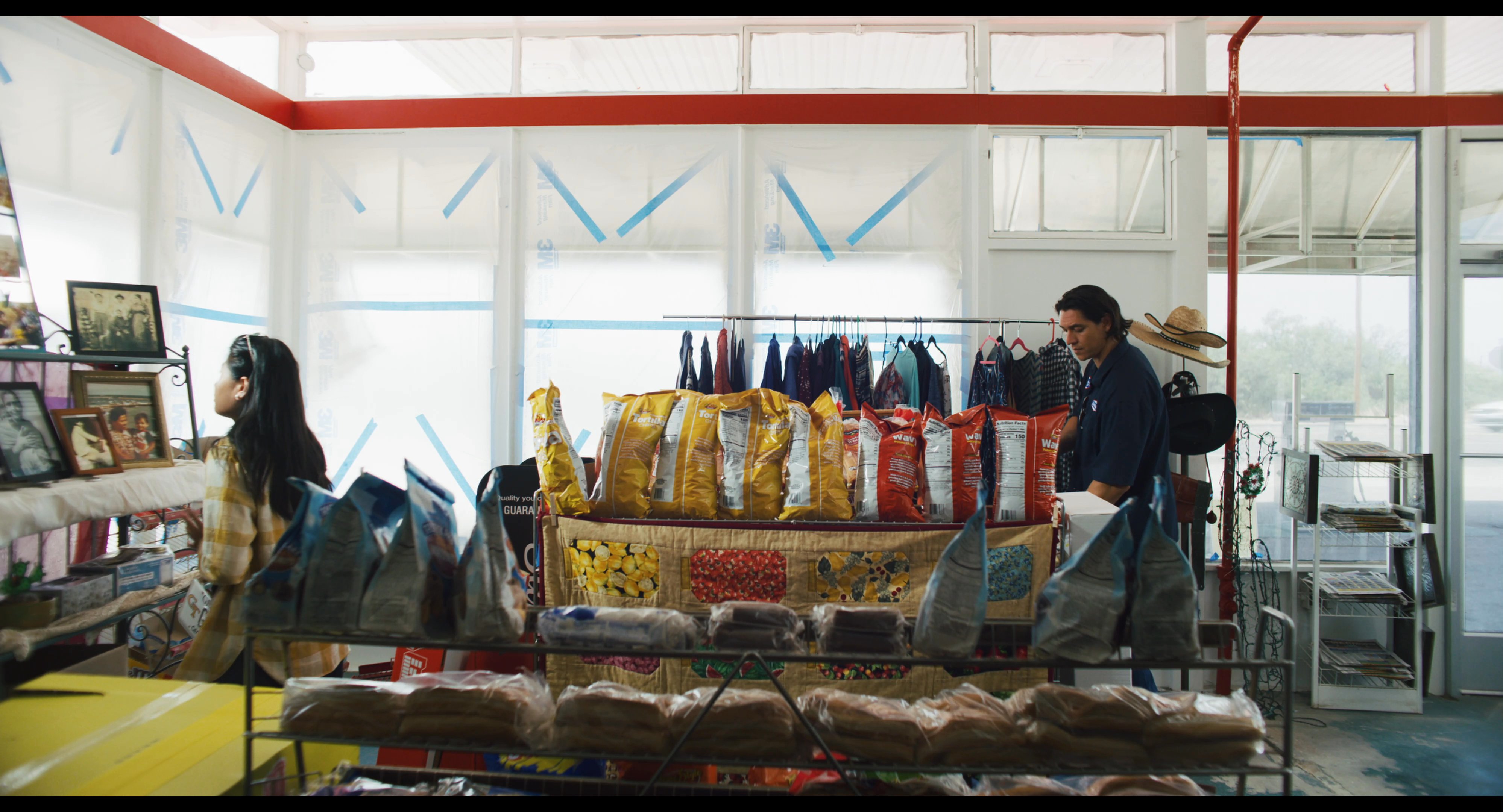 A customer interacts with a store employee at a retail counter before shifting focus to a collection of nostalgic family photographs displayed nearby.