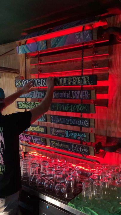 Skinny Bar - Owner Grant showing us the craftsmanship of the tiki bar handmade menu board - Comedy Clubs Near Me - Boulder City, Nevada