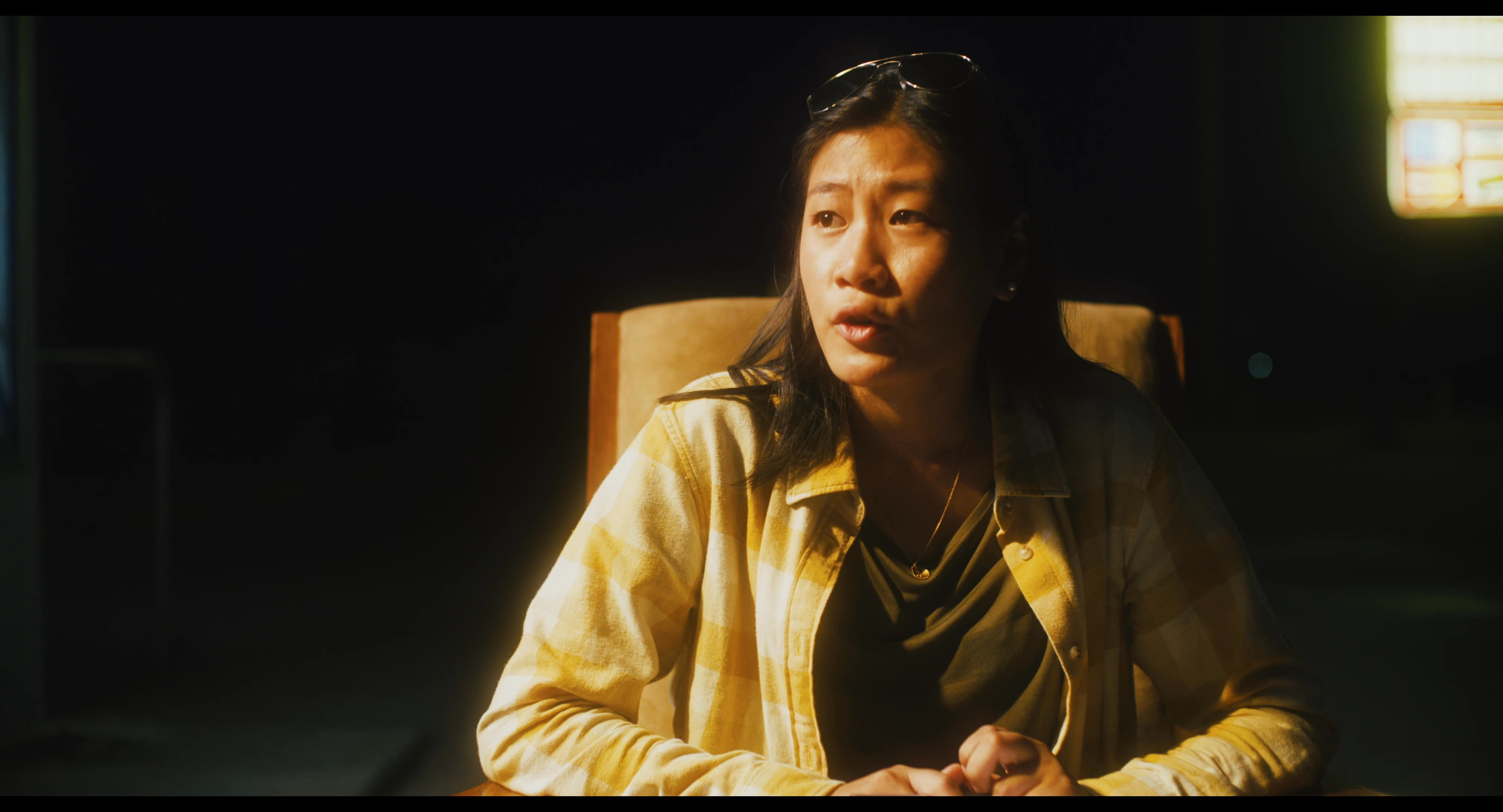 Two individuals engage in an intimate conversation while seated outdoors in a dimly lit, nocturnal setting. The lighting emphasizes the subjects' expressions as they exchange dialogue.