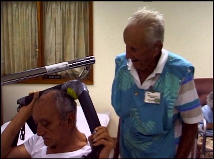 Caregivers demonstrate the use of a patient lift system in a medical setting, transitioning to a scenic outdoor view of a rainbow over the coastline.