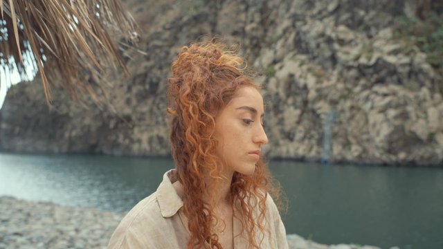A sad girl standing by the riverside