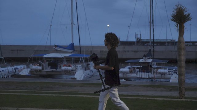 Filmmaker walking past yachts