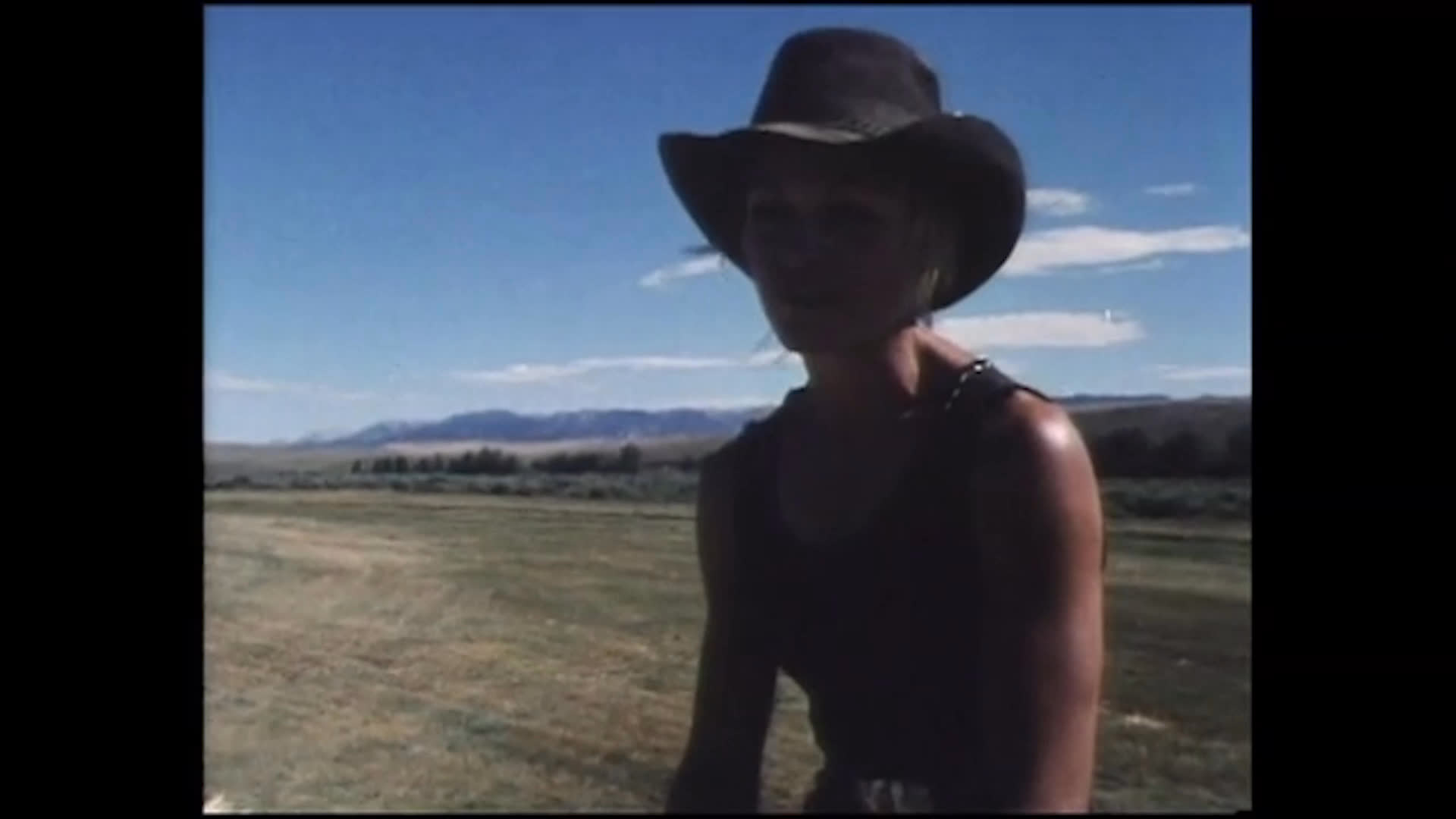 A woman in a cowboy hat speaks from an open ranch landscape about fall cattle work and her grandparents’ ranch. The sequence includes old photographs of riders on horseback, recalling her time growing up around ranch life.