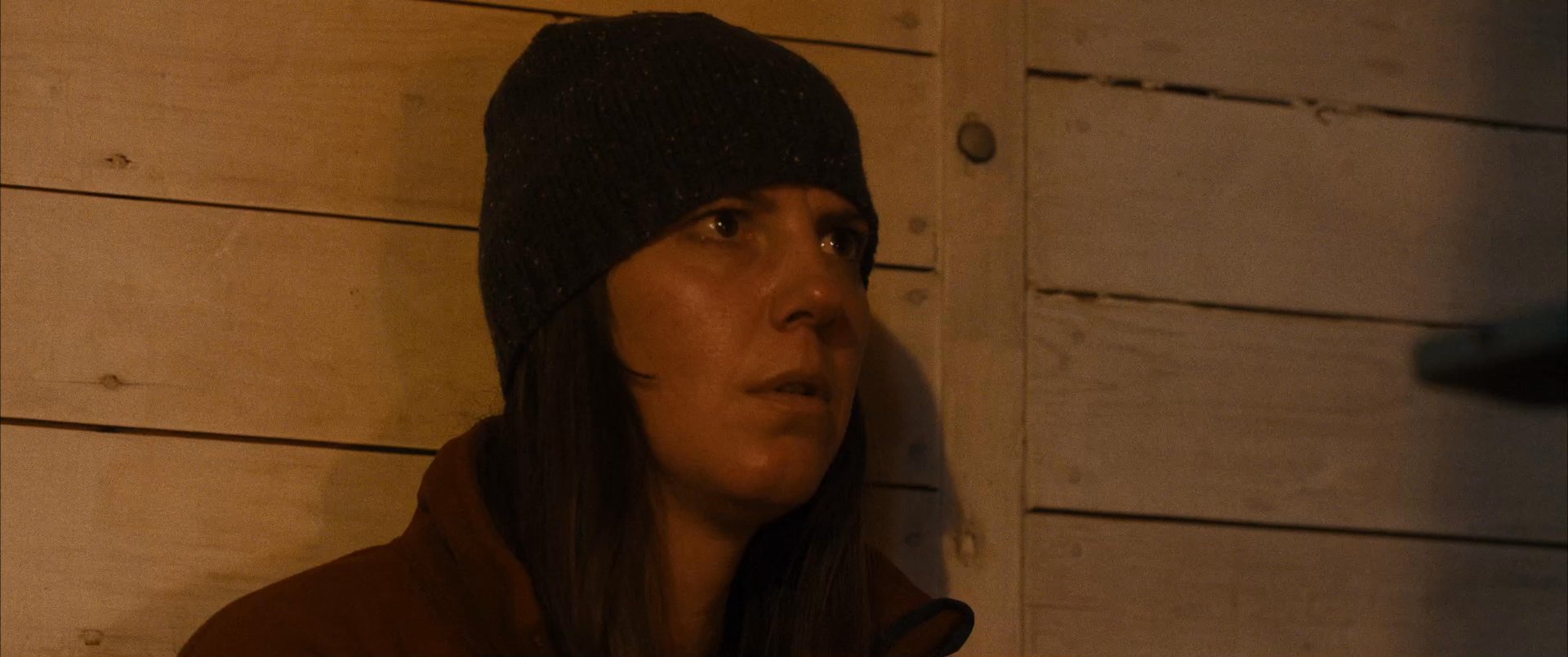 Two people discuss hiking photos on a smartphone while relaxing together inside a rustic cabin environment.