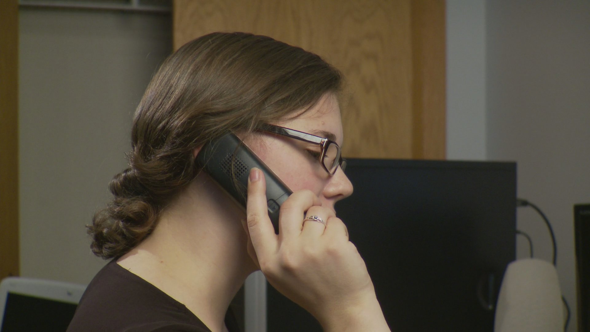 Two individuals conduct separate telephone conversations in interior environments before one transitions to driving a white sedan.