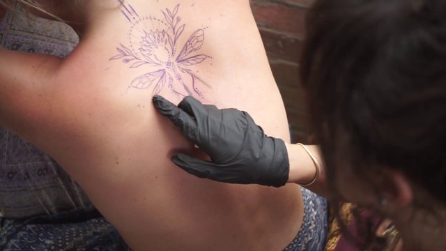 Tattoo artist working on back tattoo