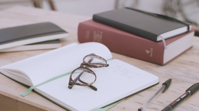 Glasses and notebooks on a desk