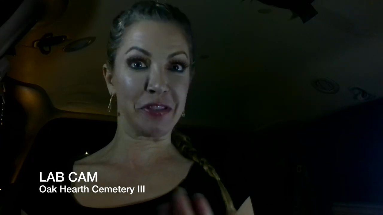 Host Dee Weiss prepares for a paranormal investigation at Oak Hearth Cemetery, explaining the equipment and mission parameters for the segment.