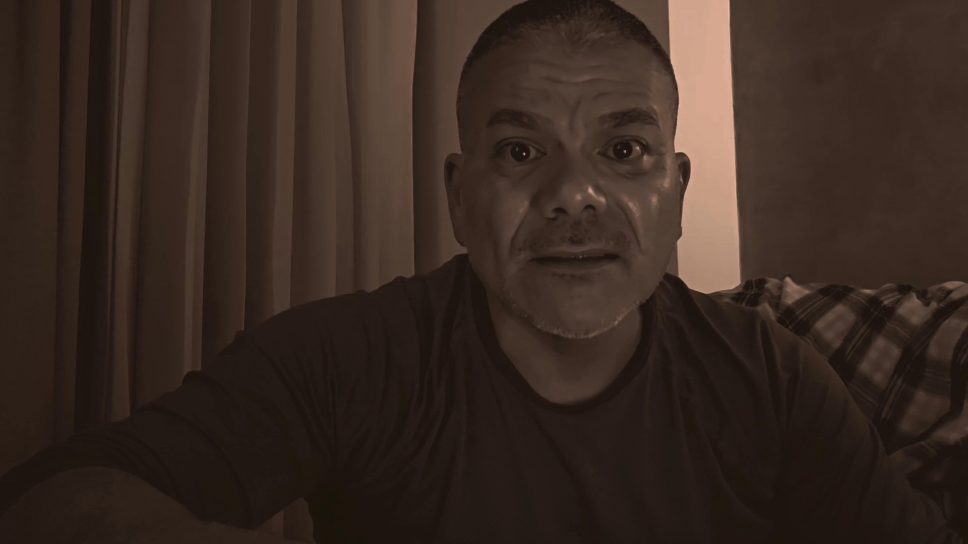 A man engages in a direct-to-camera conversation, sharing thoughts or observations with an unseen audience. He maintains consistent eye contact and expressive gestures throughout the sequence.